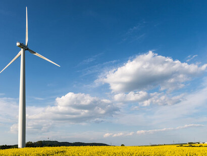 A scenic view of wind turbines rising above blooming canola fields in Germany