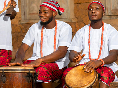 Nigerian men gathered around traditional drums, highlighting how heritage binds communities beyond religious labels