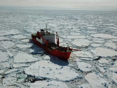 A red nuclear icebreaker navigating among floating icebergs