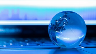 A glass globe resting on a laptop keyboard, representing the growing role of technology in shaping geopolitical strategy