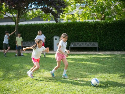 Young children joyfully playing football on an open field
