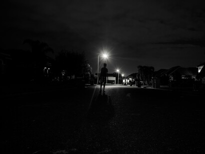 A lone figure stands in a dimly lit street, their shadow stretching before them, a reminder that true self-awareness begins when we stop running from what lurks in the dark