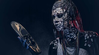 A person from an indigenous African tribe wearing traditional makeup and costume while staring at a mask in their hand, symbolizing the struggle of the modern African youth caught between tradition and modernity