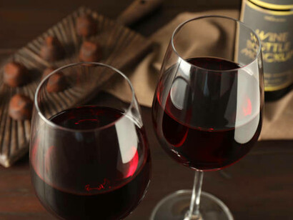 Red wine glasses accompanied by rich chocolate candies on a wooden table, perfect for pairing