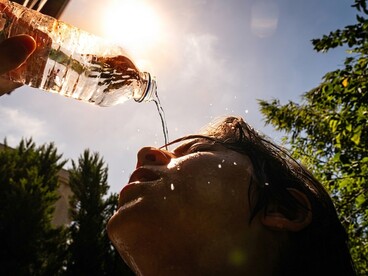 A woman pours water over her face to cool down on a hot summer day
