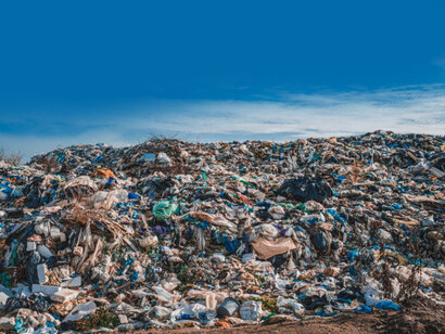 Overflowing with trash and plastic, a sprawling landfill beneath a bright blue sky highlights the pressing issue of poor waste management and its threat to the environment