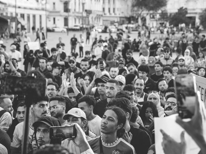 A protesting crowd captured in black and white, with many people filming on smartphones, Morocco