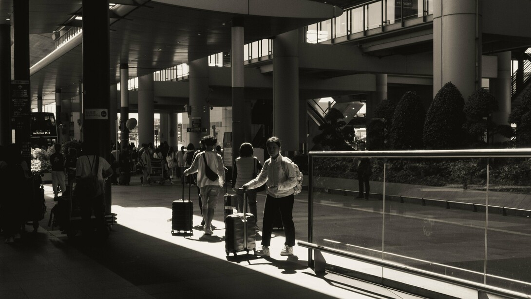People arriving and departing with suitcases, representing the human movement behind economic growth
