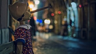 Una statua di Pinocchio, seduta su una panchina in una via notturna illuminata da luci soffuse