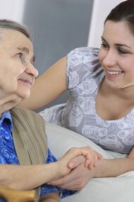 Una anciana toma la mano de su cuidadora
