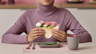 Adult seen from the front holding a sandwich filled with flowers