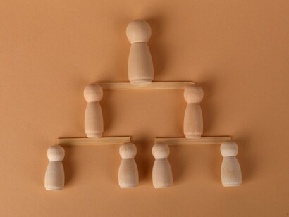 A wooden hierarchy built from figures standing on separate levels, reflecting the balance between leadership, authority, and the dignity of those who follow
