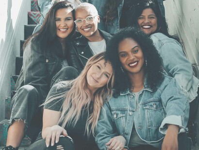 A group of close female friends sitting on the stairs mostly presenting different smiles from the happ to the content to the ecstatic 