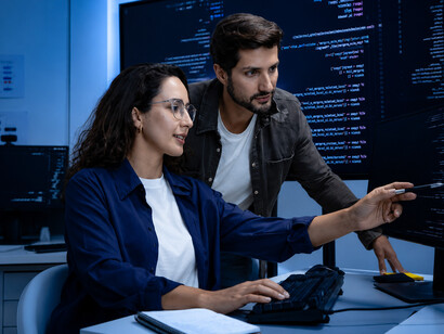 A team of professionals closely examining network and performance data on computer screens in a server room