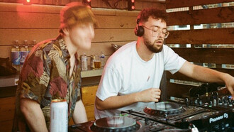 A bespectacled DJ spins mesmerizing beats, while the man beside him dances with unbridledly