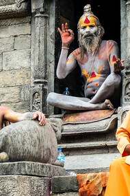 Three monks resting on the concrete steps of Pashupatinath Temple during the daytime, embodying the serene spirituality of Kathmandu, Nepal