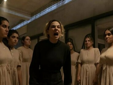 A protagonista de Bom Dia, Verônica aparece em primeiro plano, em uma cena de forte tensão, cercada por mulheres em um ambiente fechado. A série explora violência, segredos e relações de poder a partir de uma perspectiva marcada pelo suspense psicológico