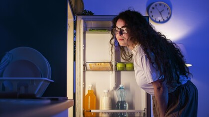 A woman studying her fridge, symbolizing the need to look deeper than dates and cool air