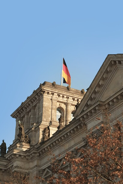 The German flag flying in front of the Reichstag building in Berlin, Germany