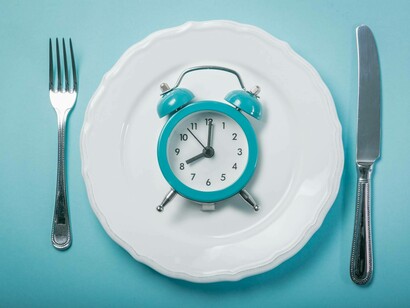 A table set of utensils, a plat and a clock on it waiting to break the fast