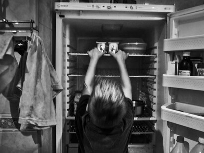 Un niño buscando comida en una nevera medio vacía