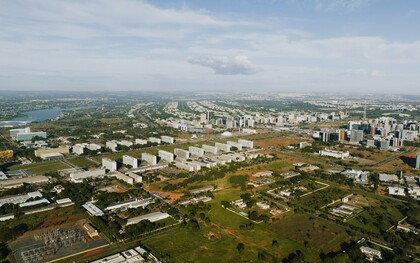 Do alto, Brasília revela o contraste entre o desenho urbano planejado e a expansão que se estende para além de seus limites. Ao fundo, as cidades-satélite aparecem distantes do núcleo original, evidenciando como o crescimento efetivo pode assumir trajetórias diferentes daquelas previstas pelo planejamento
