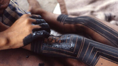 A Kayapó woman painting her daughter’s legs with genipa americana and charcoal. Photo: Darrell Posey, circa 1986. © Pitt Rivers Museum, University of Oxford (2001.82.1362).