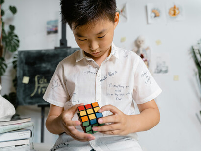 Un garçon concentré sur un cube Rubik, illustrant le processus cognitif dynamique et incarné, en lien avec les boucles perception-action et l'exploration d'affordances dans l'approche 4E