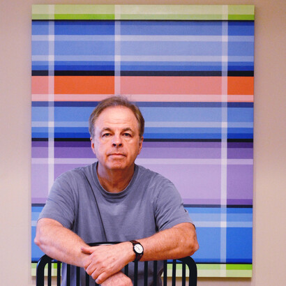 Mark Travers' sits in front of one of his works of art