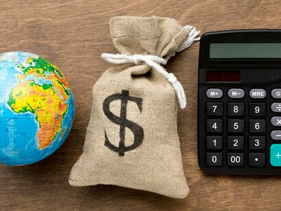 A burlap sack of money and a calculator symbolize the intersection of finance and global economic planning. This image highlights the importance of financial management in navigating the complexities of the global economy