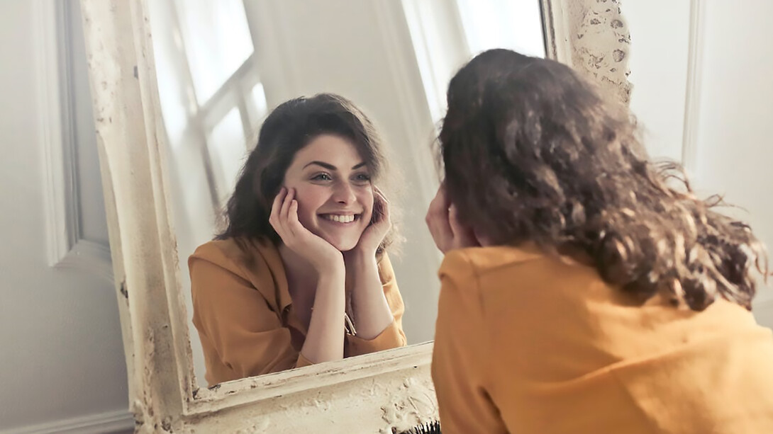 Happy and positive woman looking in the mirror