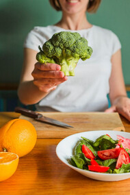 A women showcasing a variety of rich nutrient vegetables and fruits  providing a more successful cleanse