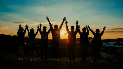Silhouettes of people holding hands at sunset, symbolizing unity and togetherness