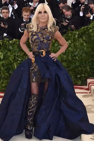 Donatella Versace in an intricately embellished ensemble, symbolizing the luxury and theatrical elegance of the Versace house