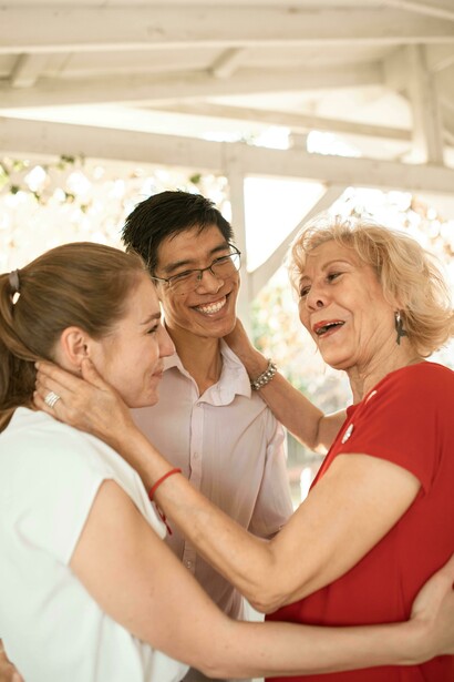 An elderly woman speaking with a couple