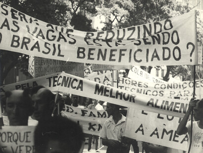 Protestantes erguem faixas nas ruas em marcha durante anos da Ditadura Militar na Brasil. Descubra como o viés ideológico pode distorcer a representação dos eventos históricos no ensino do Tempo Presente