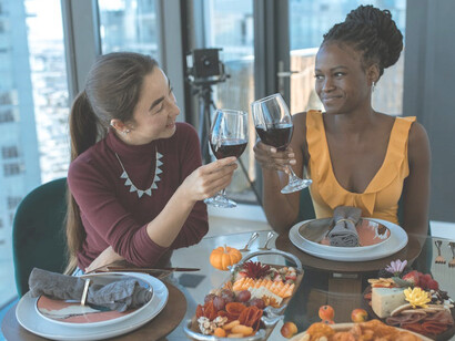 Two women savor wine and taste cheese at an elegantly set wine table