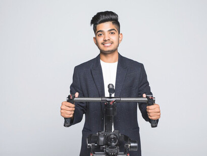 A young filmmaker smiles proudly while holding his camera, symbolising the untapped potential of Pakistan’s creative talent waiting for the right opportunities