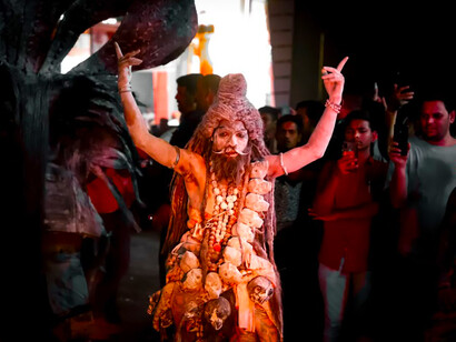 A man dressed in a costume stands in front of a group of people performing the Shiva dance in Jodhpur, India