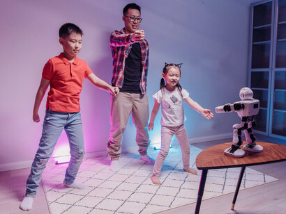 A family dancing together, their attention drawn to a nearby robot
