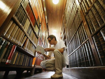 Un chico coge un libro de la estantería de una biblioteca