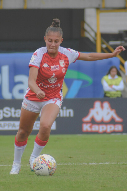 Photograph of women playing soccer during a competitive match, highlighting female sports
