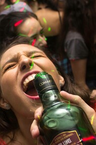 Young woman drinking alcohol from a bottle at a party