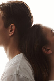 A man and woman share a tender moment of love as she rests her head on his back, her eyes peacefully closed