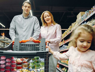 Mother guiding her child through a payment at the supermarket during a family shop
