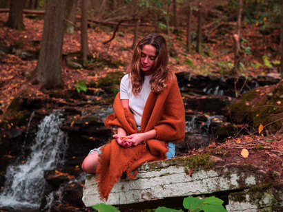 Mujer sentada en una roca frente a un riachuelo