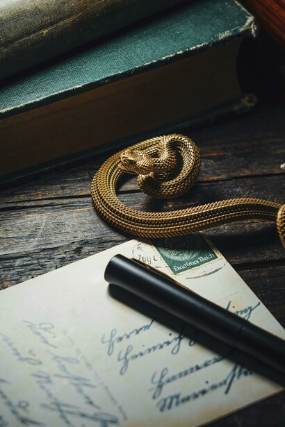 A vintage-inspired composition with a bronze snake ornament resting beside an old envelope and a handwritten letter, evoking nostalgia and timeless love