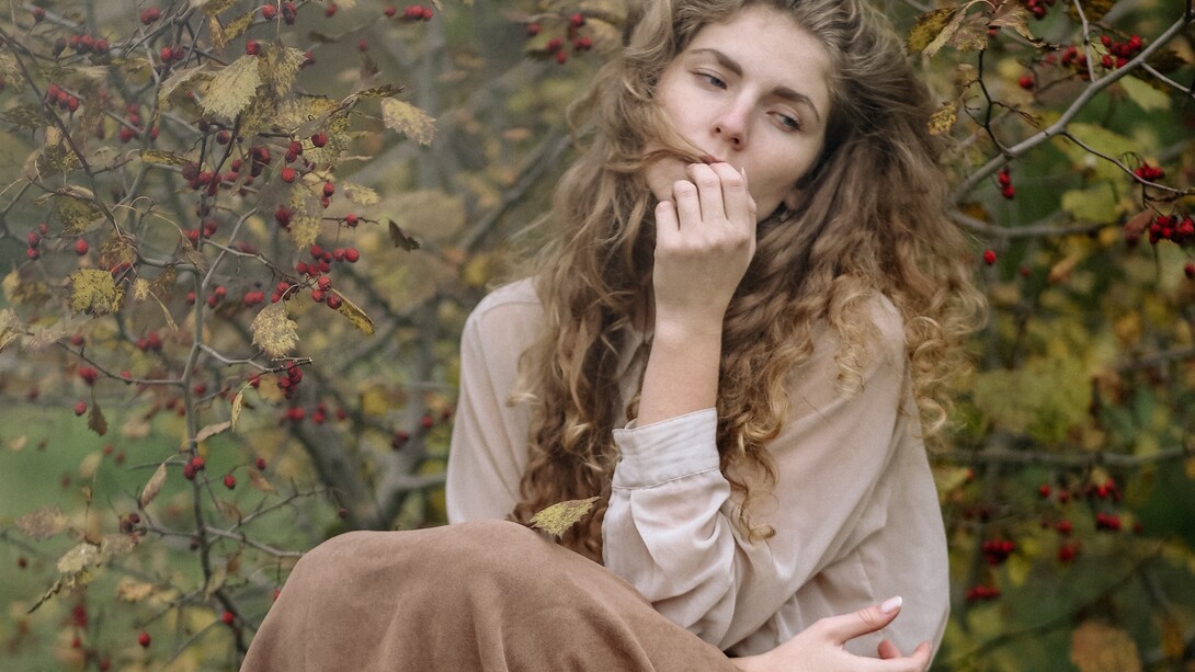 A woman, sitting in the middle of a forest, thinking and wondering about her life choices