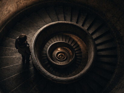 A solitary figure stands within a spiraling descent, already moving deeper into a path that no longer feels optional