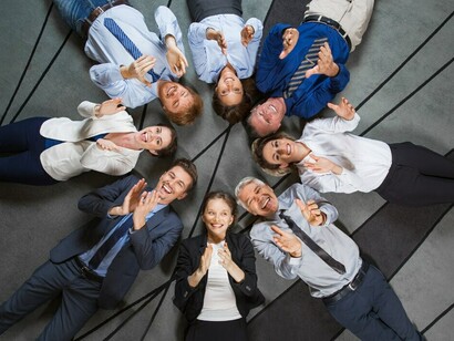 A diverse group of professionals lying on the floor and clapping, showcasing the importance of corporate inclusion and the intersectional approach to social justice and equality